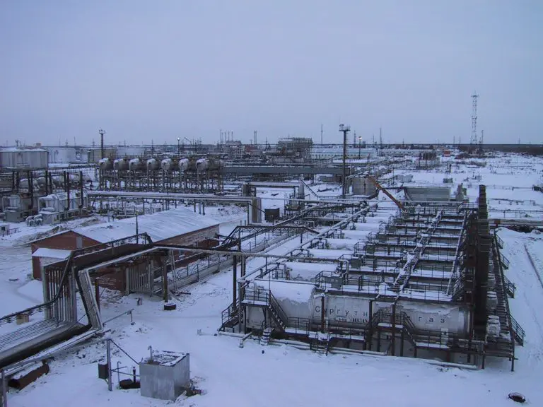 A large oil field with many tanks in the snow.